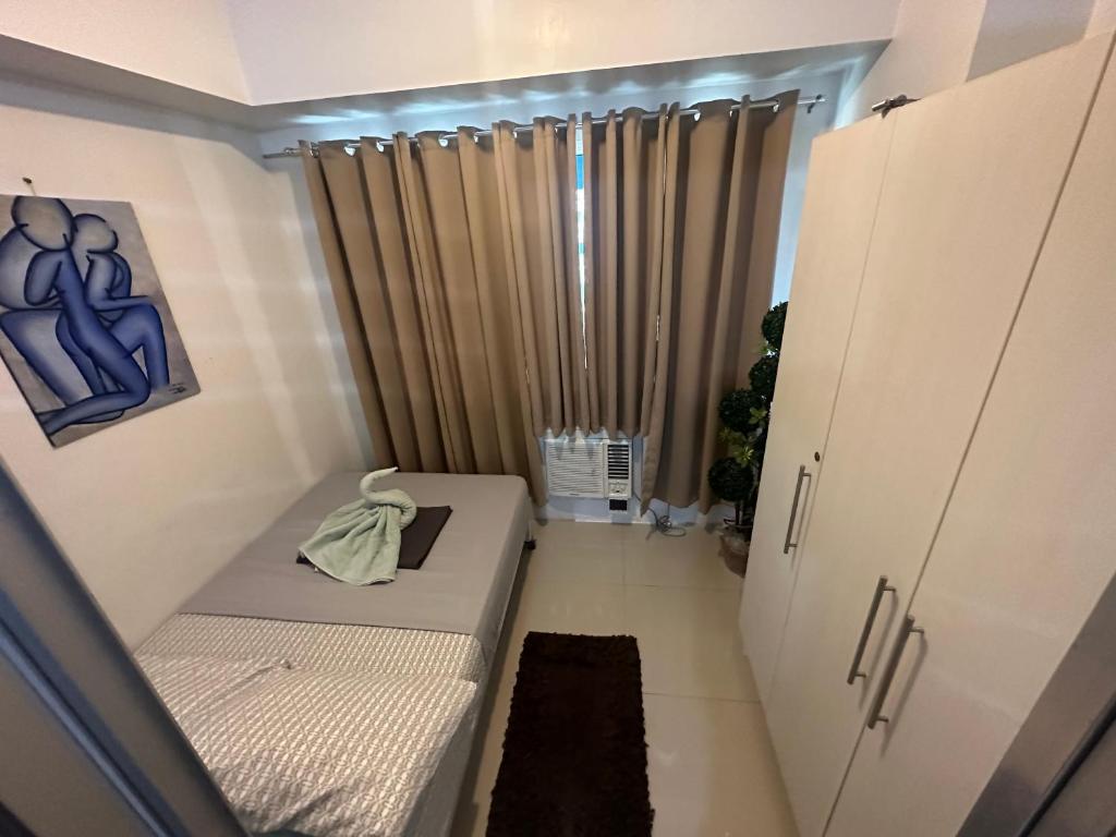 ein kleines Zimmer mit einem Bett und einem Vorhang in der Unterkunft Staycation for you at Casa Amara near MOA in Manila