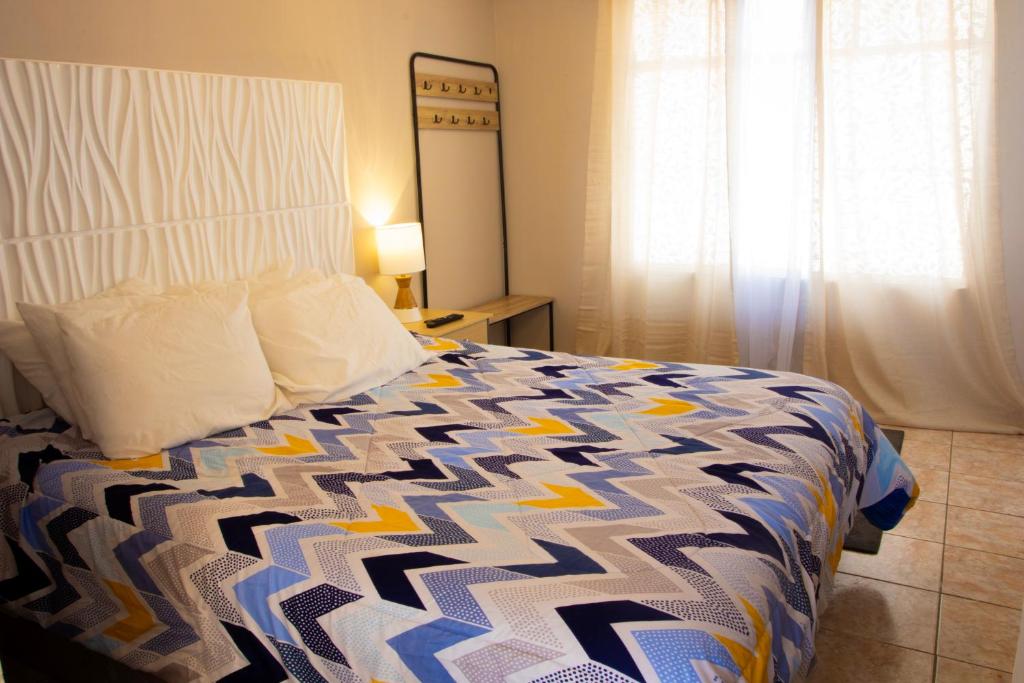 a bedroom with a bed with a blue and white comforter at Apto Vista Hermosa con terraza ajardinada privada in Sololá