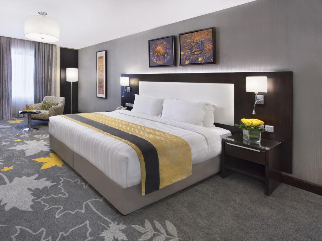 een hotelkamer met een groot bed en een stoel bij Warwick Hotel Jeddah in Jeddah