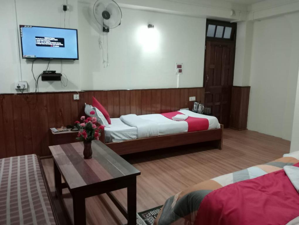 a bedroom with two beds and a table and a tv at HOTEL TASHI NORLING Near Mall Road in Gangtok