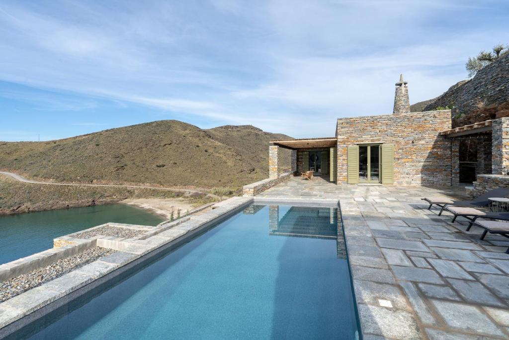 a swimming pool next to a house with mountains at Triad Villas in Ioulis