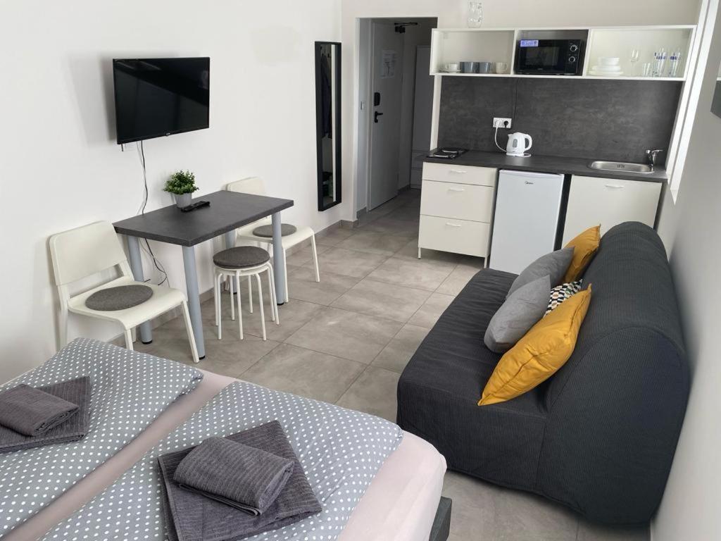 ein Wohnzimmer mit einem Sofa und einem Tisch sowie eine Küche in der Unterkunft Apartmán HARMONY - Lipno nad Vltavou in Lipno nad Vltavou