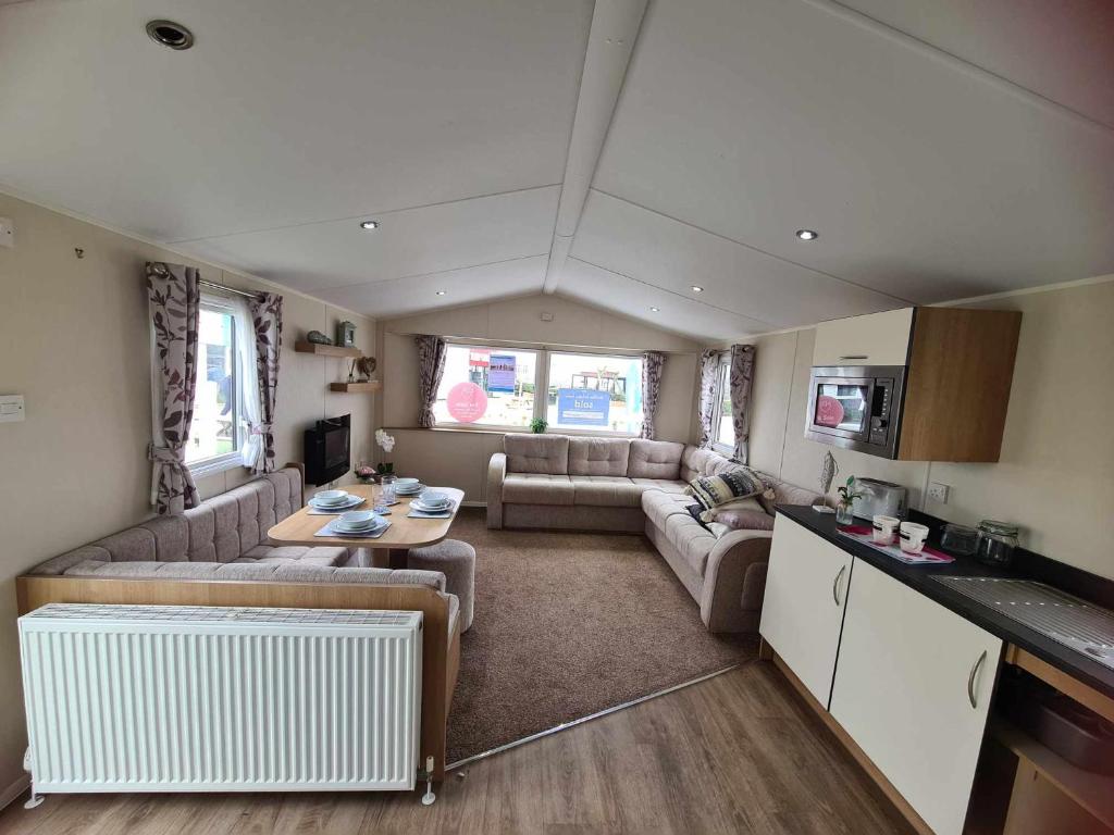 a living room with a couch and a table in a caravan at Happy Days Caravan Primrose Valley in Filey