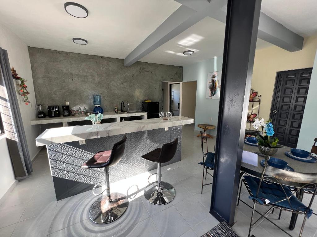 a kitchen with a bar with stools around it at Apartamento pichones in Comitán