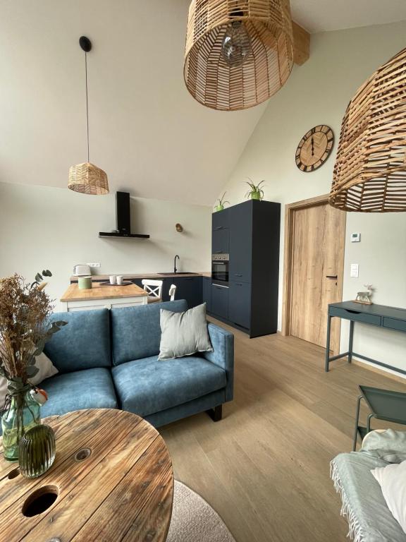 ein Wohnzimmer mit einem blauen Sofa und einem Tisch in der Unterkunft La Grange d'Haversin in Ciney