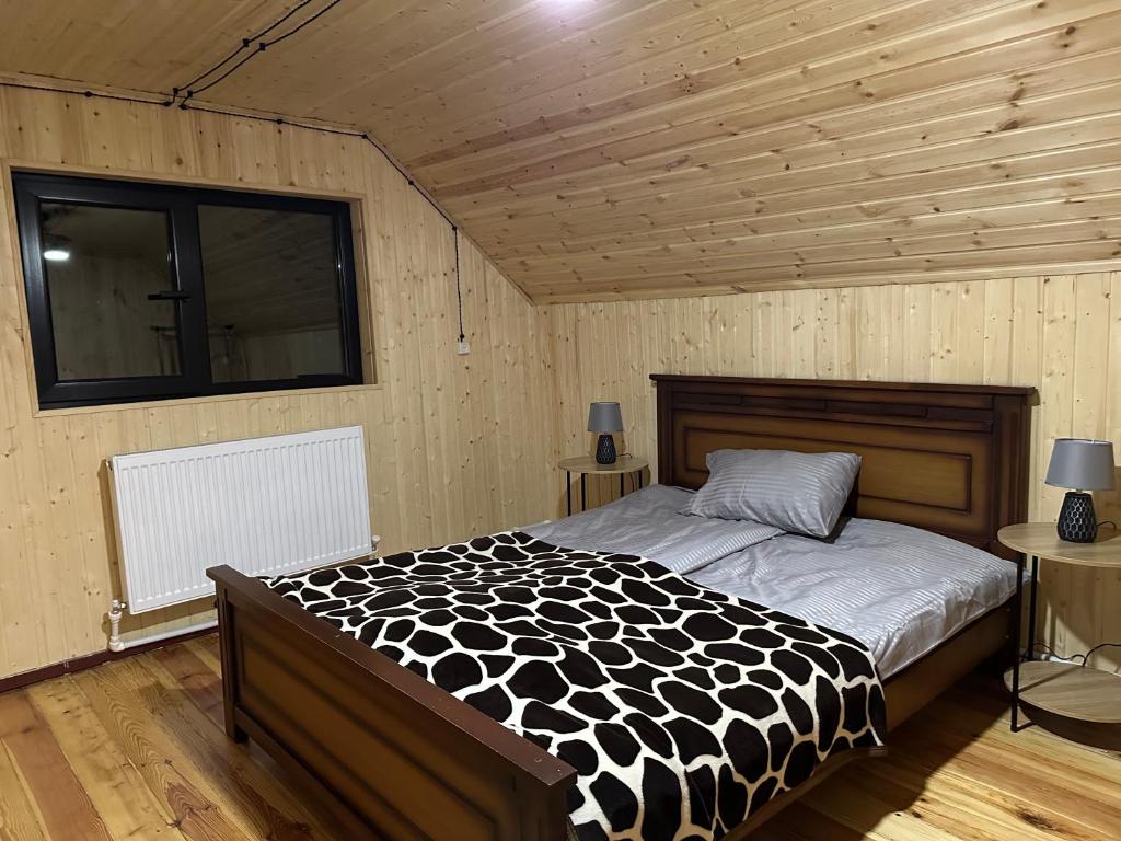 a bedroom with a bed with a black and white comforter at Cozy Wooden House in Kiket'i კიკეთი in Kiketʼi