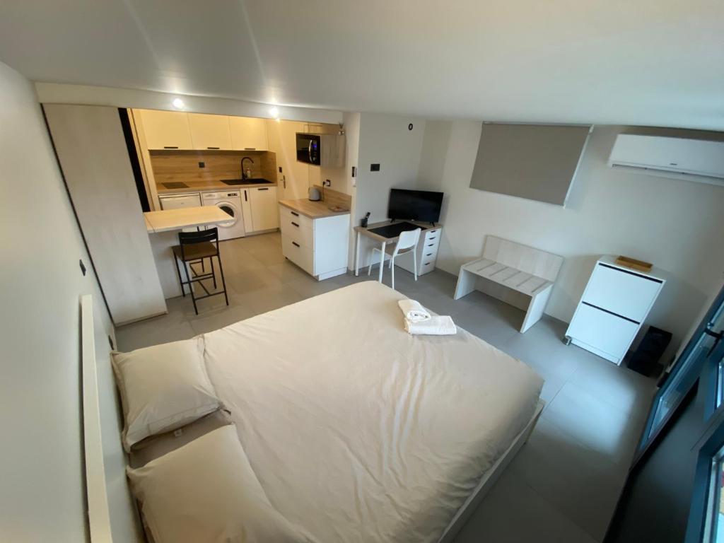 1 dormitorio con 1 cama blanca grande y cocina en Studio chez l'habitant avec piscine commune, en Grièges