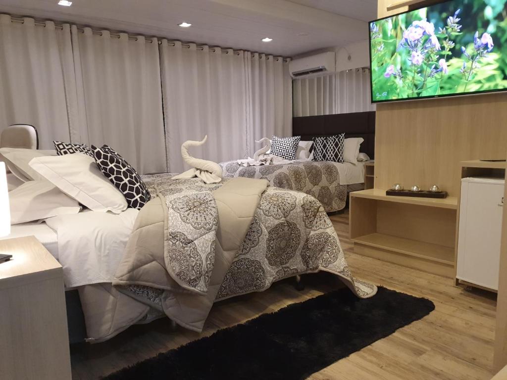 a bedroom with two beds and a flat screen tv at Lages Plaza Hotel in Lages