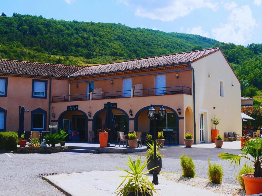 ein großes Gebäude mit einem Berg im Hintergrund in der Unterkunft Hotel Restaurant Les Chataigniers in Privas