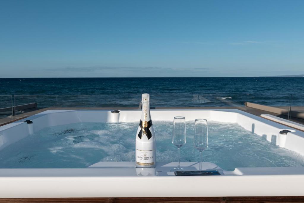 una bottiglia di vino e due bicchieri in una vasca idromassaggio di Kavo Seaside Luxury Apartment ad Argásion