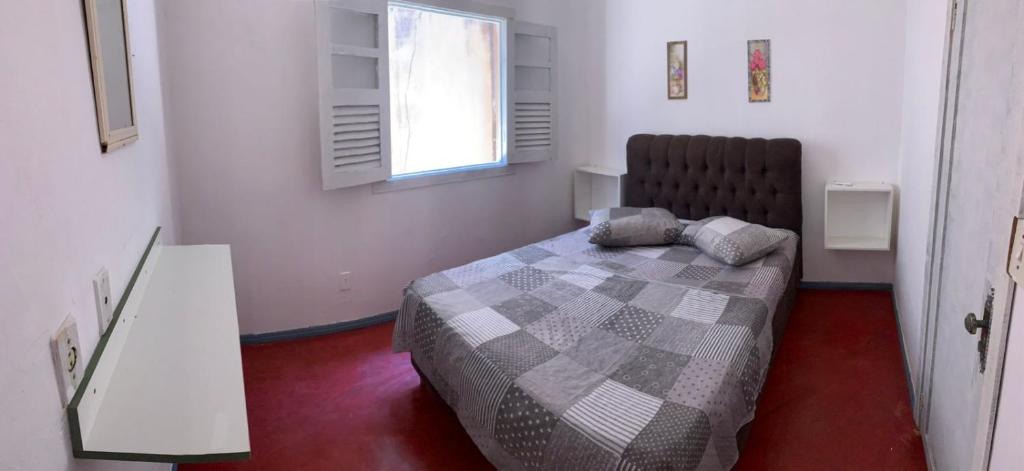 een slaapkamer met een bed en een raam bij Pousada Tropical in Marataizes