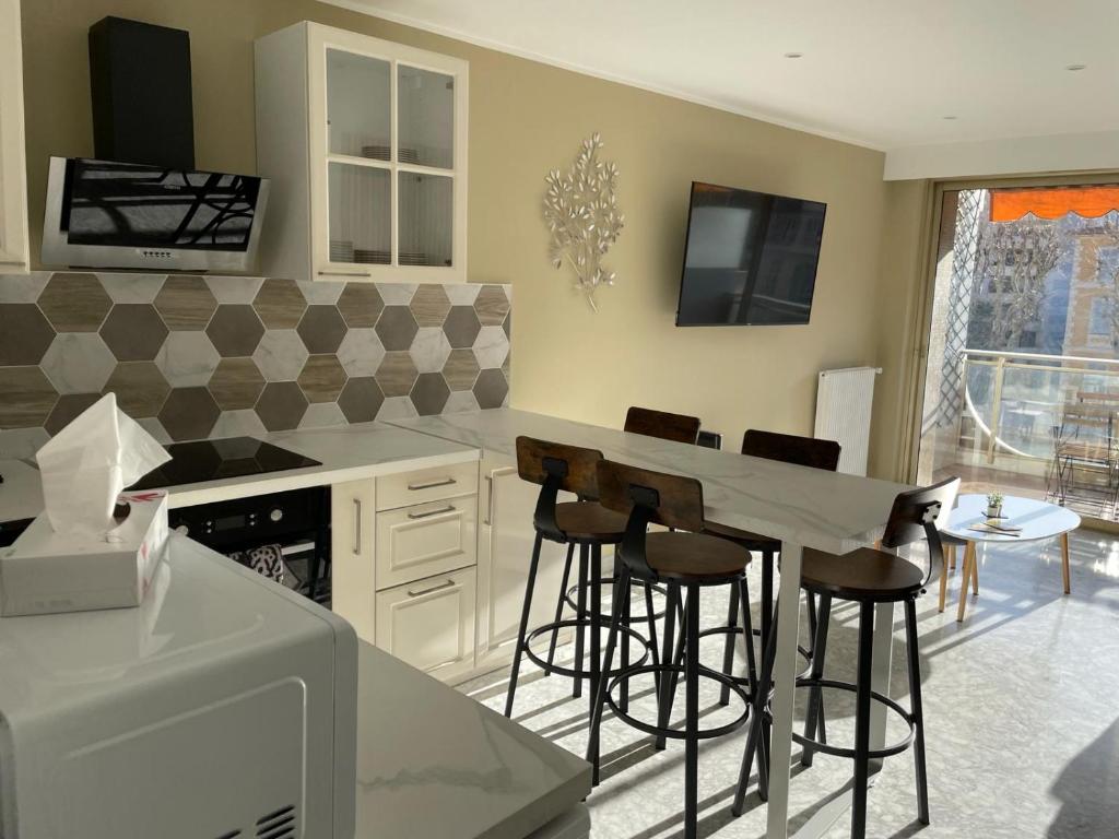 une cuisine avec un comptoir et des tabourets de bar dans l'établissement Le REGENCY, appartement familial au cœur du centre-ville, des célèbres jardins Biovès, et seulement à 1 minute à pied de la plage, à Menton