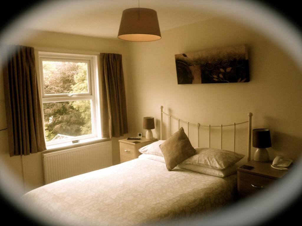 1 dormitorio con cama y ventana en Strathallan Guest House, en Helston