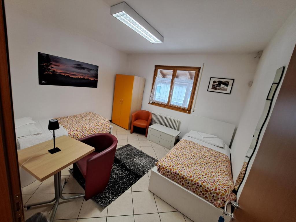 a small room with two beds and a desk at Lunga Via Delle Dolomiti in Calalzo