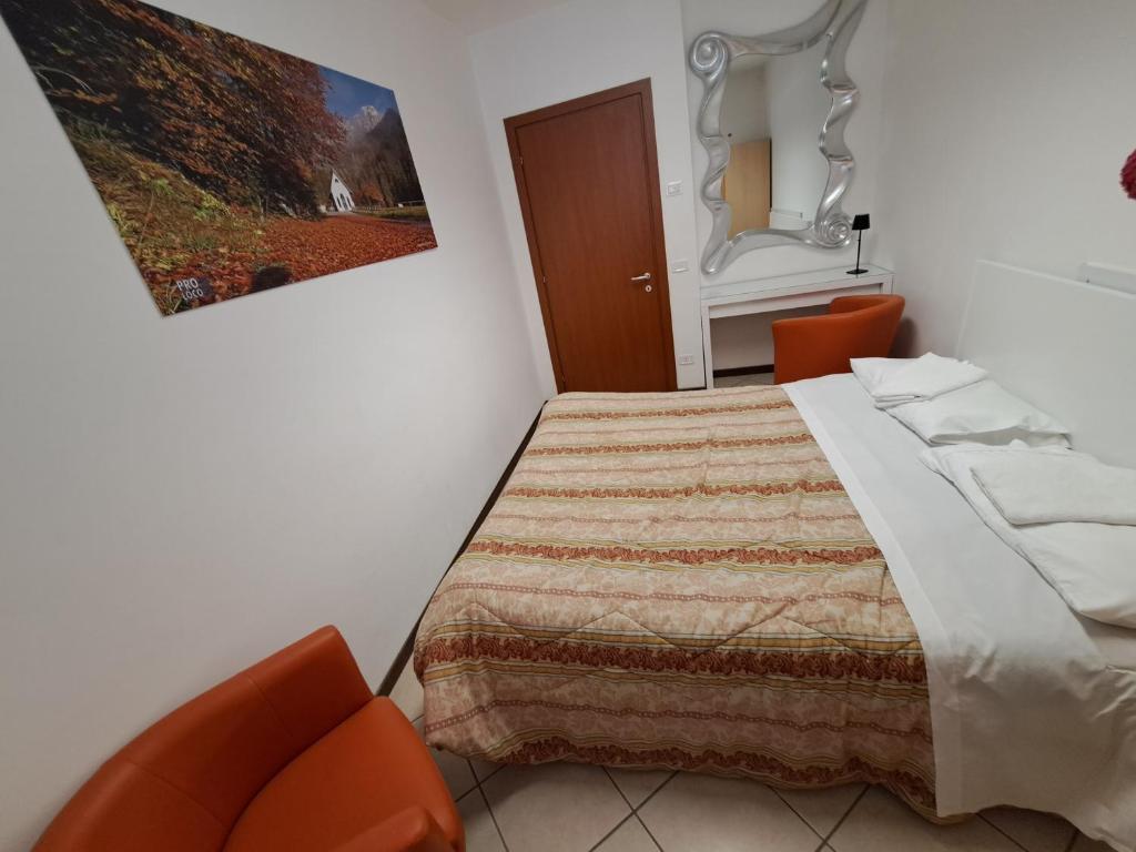 a bedroom with a bed and two orange chairs at Lunga Via Delle Dolomiti in Calalzo