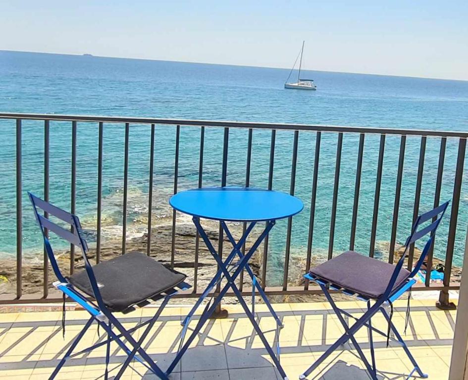 d'une table et de deux chaises sur un balcon donnant sur l'océan. dans l'établissement Studio pied dans l’eau CAP CORSE ERBALUNGA, à Brando