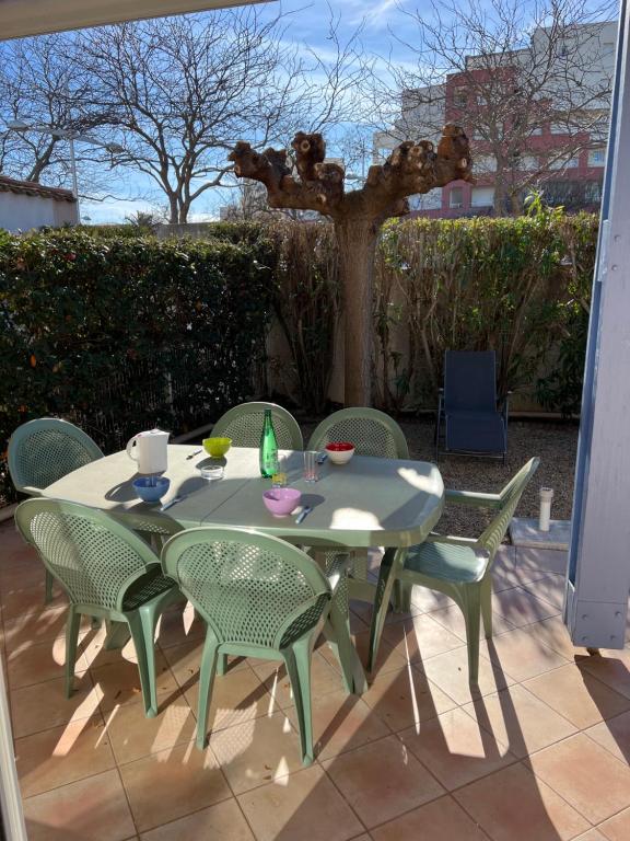 une table et des chaises sur une terrasse avec un arbre dans l'établissement LAVANDINES II Joli T3 mezzanine villa mitoyenne piscine proche plage Rochelongue Cap d'Agde, au Cap d'Agde