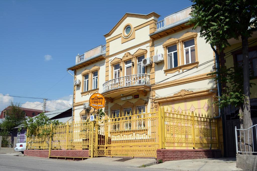a yellow building with a yellow fence in front of it at Yellow Hostel Dushanbe in Dushanbe