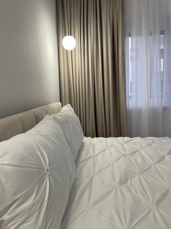a white bed with a pillow and a window at Neutral Nest in Sibiu