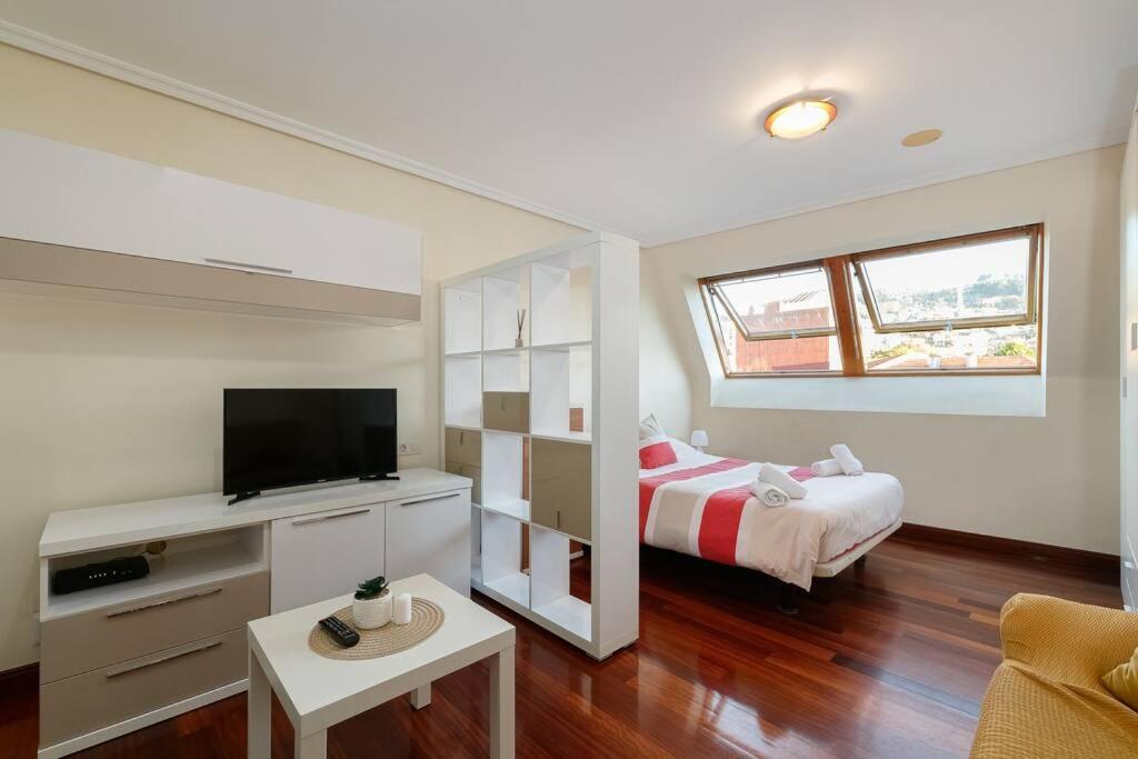uma sala de estar com uma cama e uma televisão em Luminoso ático para dos by CABANA Rentals em Vigo