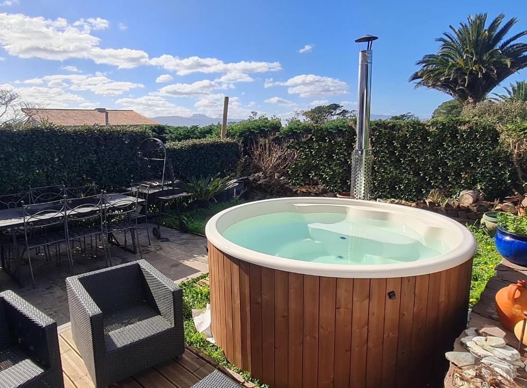 a hot tub in a yard with a table and chairs at Lodge Terre de Glisse in Saint-Jean-de-Luz