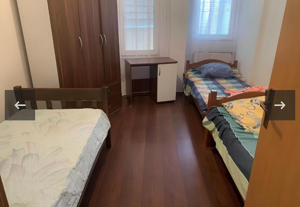 2 Betten in einem Zimmer mit einem Tisch und einem Schreibtisch in der Unterkunft Besmir in Pristina