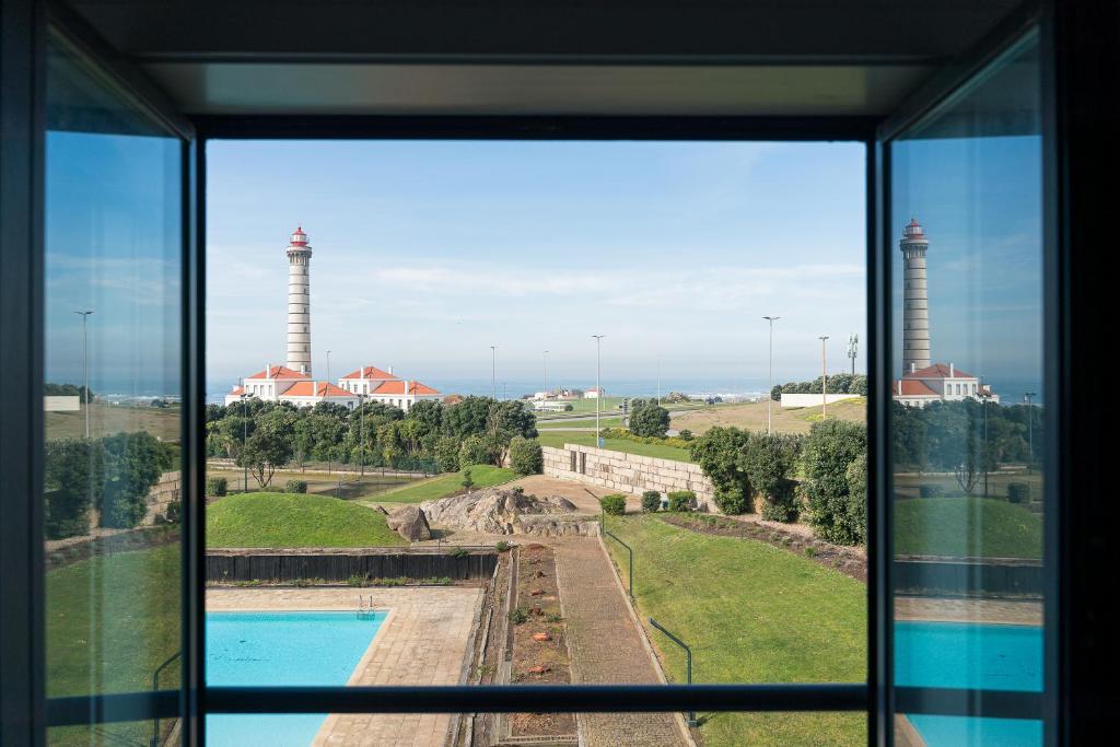 uma janela com vista para uma piscina e duas chaminés de fumo em Farol View em Leça da Palmeira