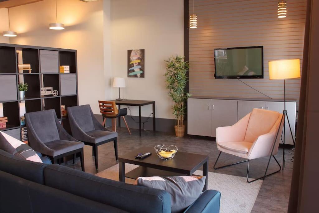 ein Wohnzimmer mit einem Sofa, Stühlen und einem TV in der Unterkunft Suite #B, Industrial Styling, AC in Halifax