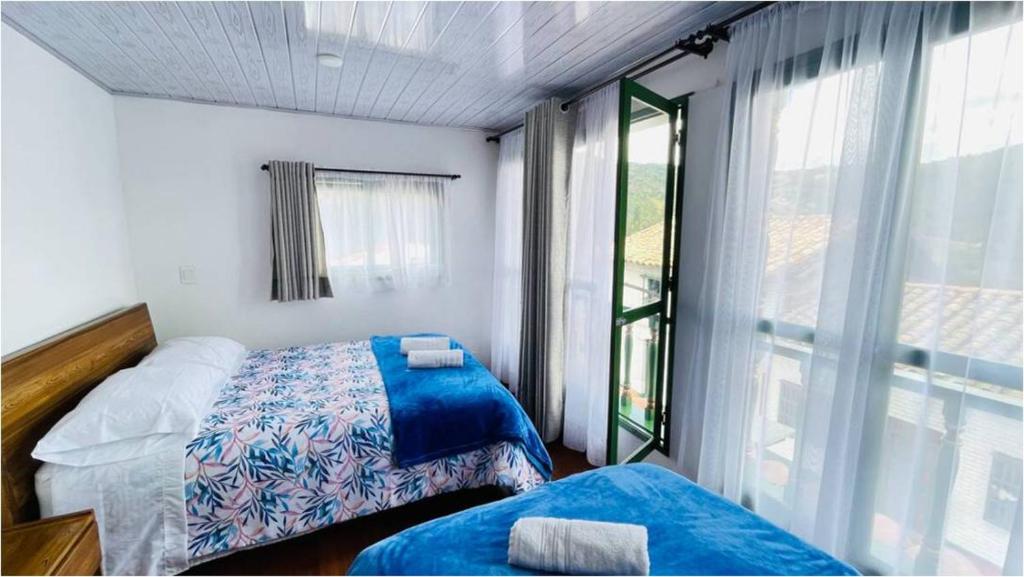 - une chambre avec 2 lits et une grande fenêtre dans l'établissement Villa Mongui, à Monguí