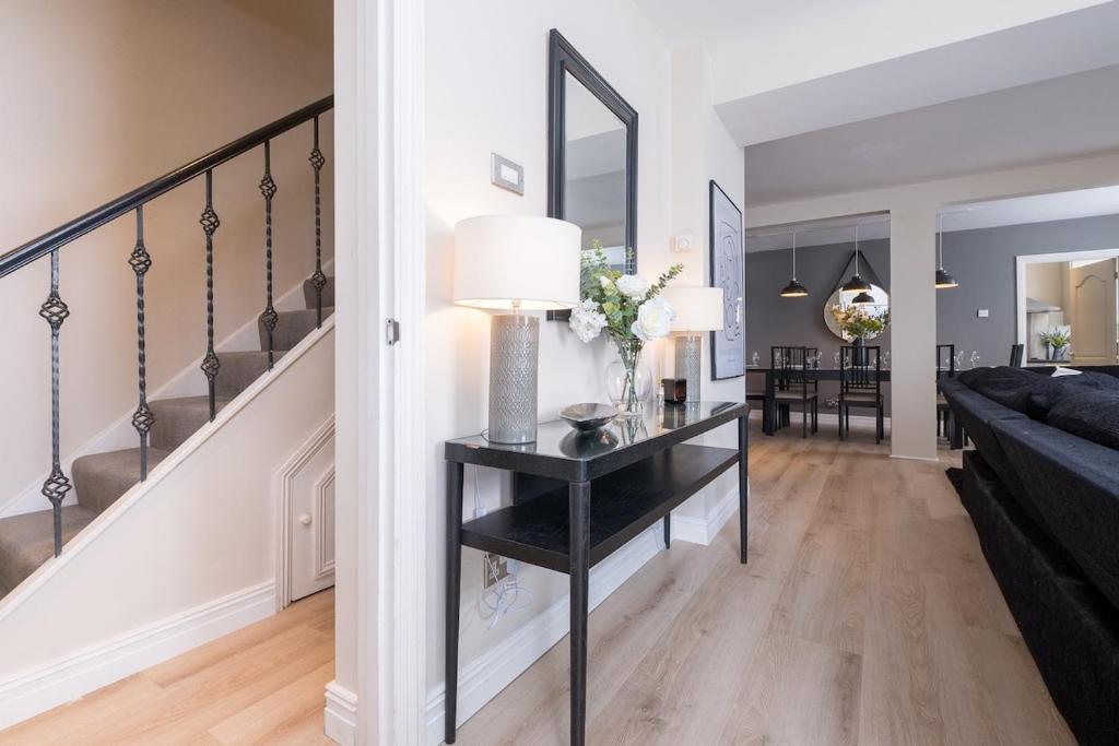 a living room with a black console table and stairs at The Hamptons by Brighton Holiday Lets in Brighton & Hove