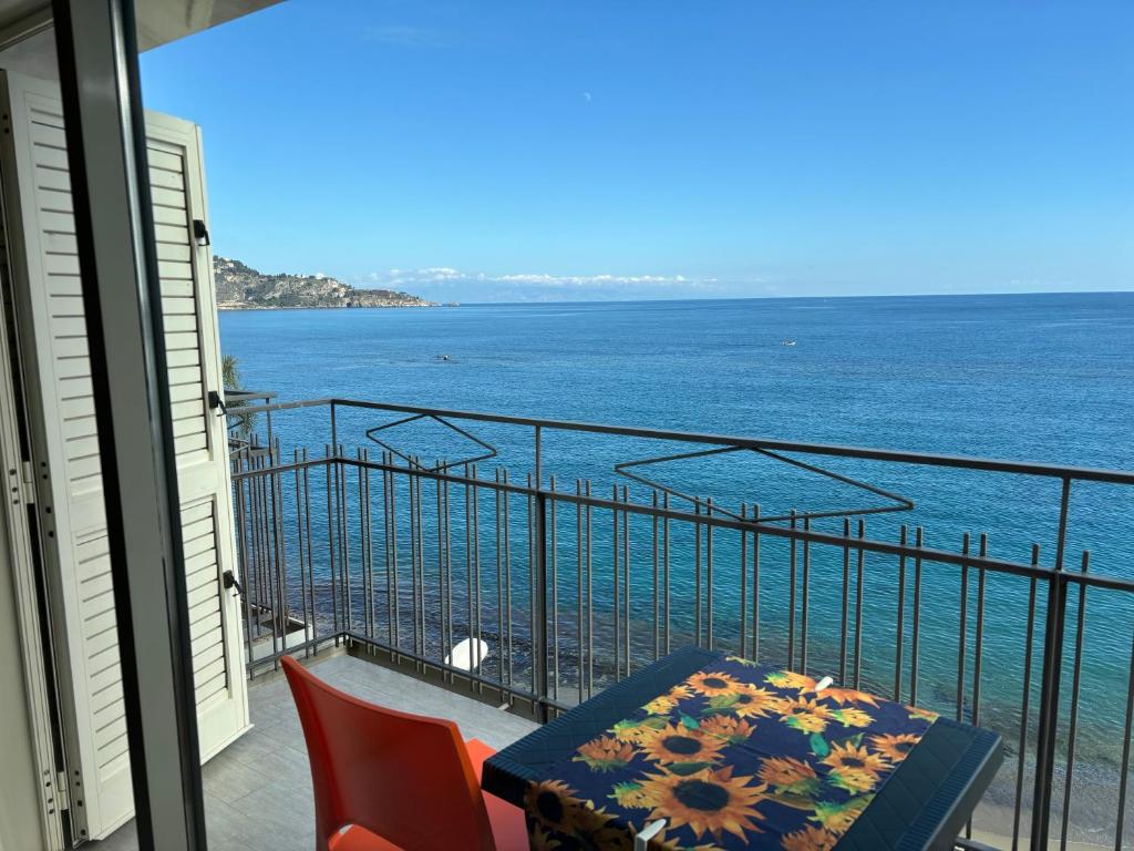balcón con mesa, sillas y vistas al océano en LA MANSARDA, en Giardini Naxos