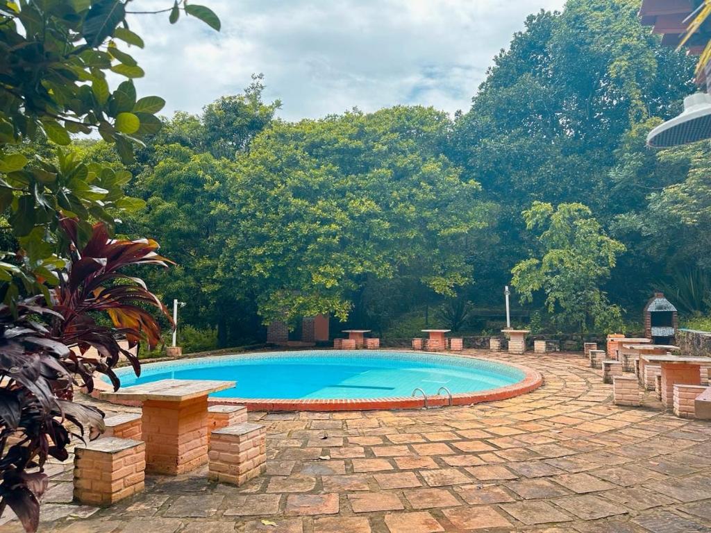 a swimming pool in a yard with trees at Encanto do Parque Hospedagem in Lençóis