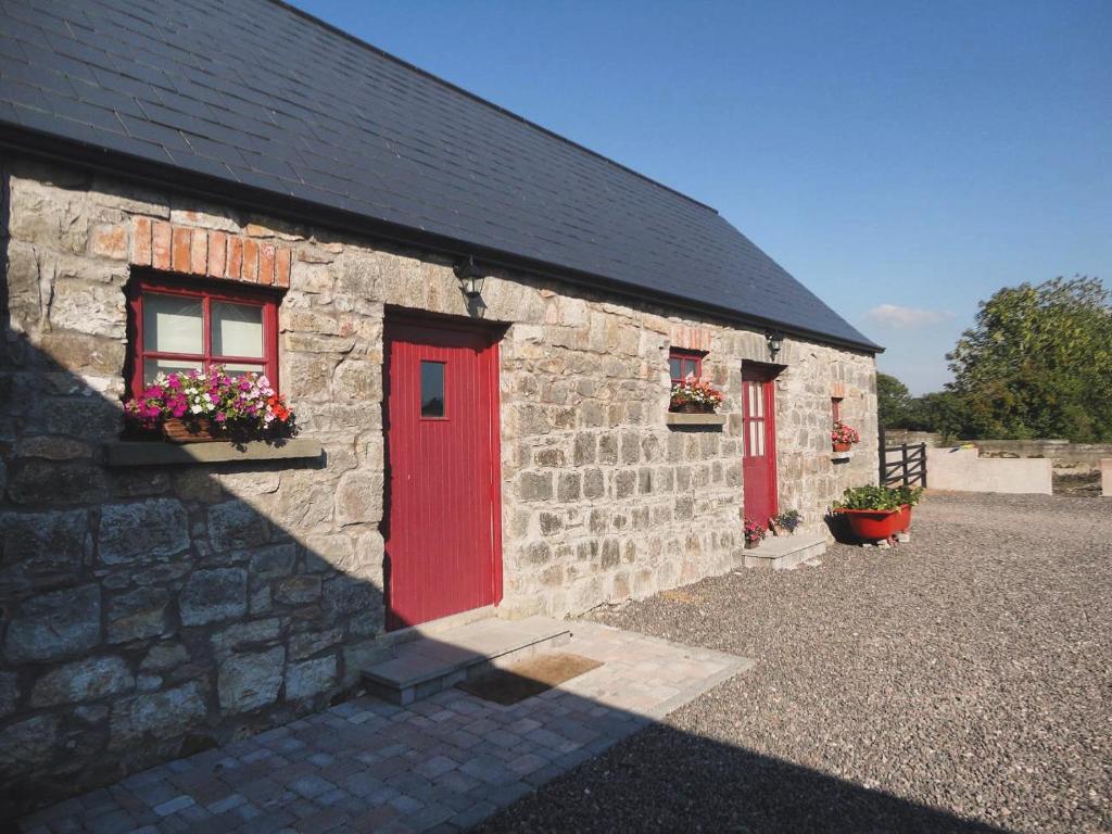 a stone building with red doors and flowers on it at Minnie’s Cottage 