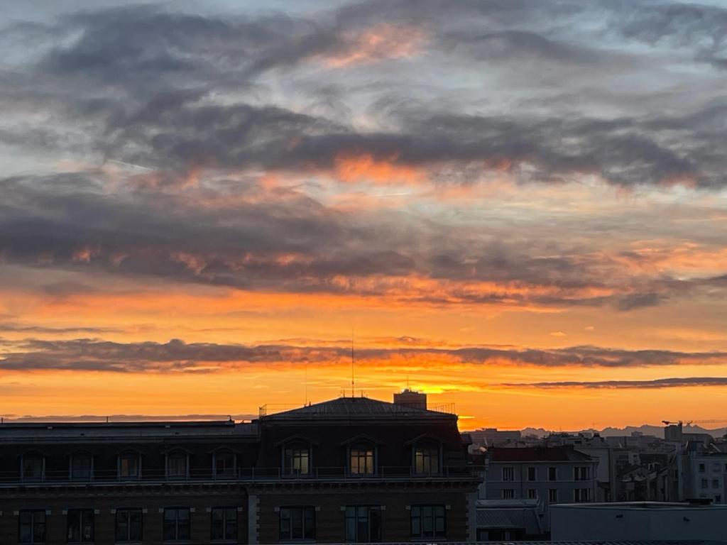 un coucher de soleil sur un bâtiment d'une ville dans l'établissement Appartement Lyon, à Lyon