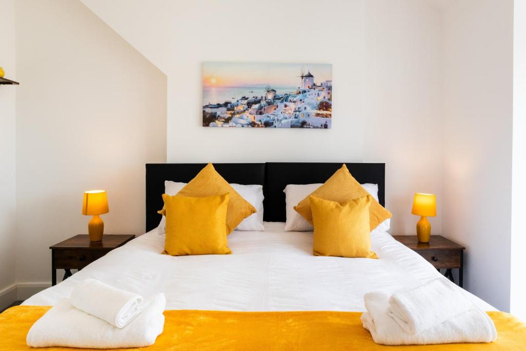 a bedroom with a large white bed with yellow pillows at Luxury House in the Heart of Mumbles Village in The Mumbles