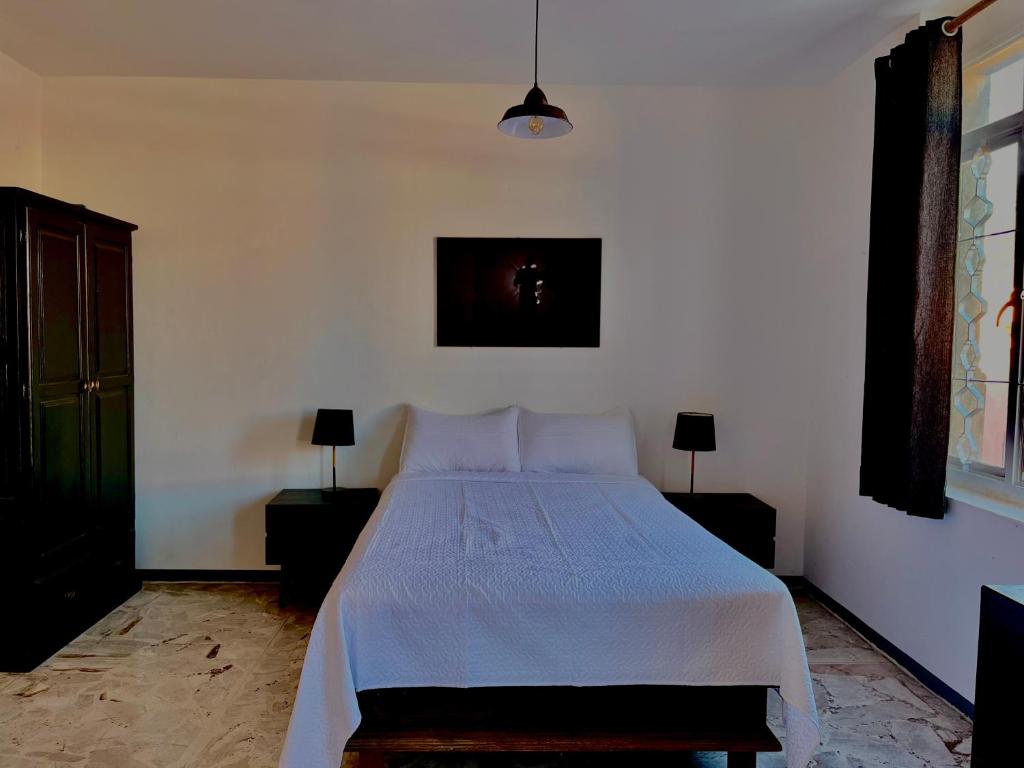 a bedroom with a white bed with two night stands and two lamps at La casona del Centro Hist. in Querétaro