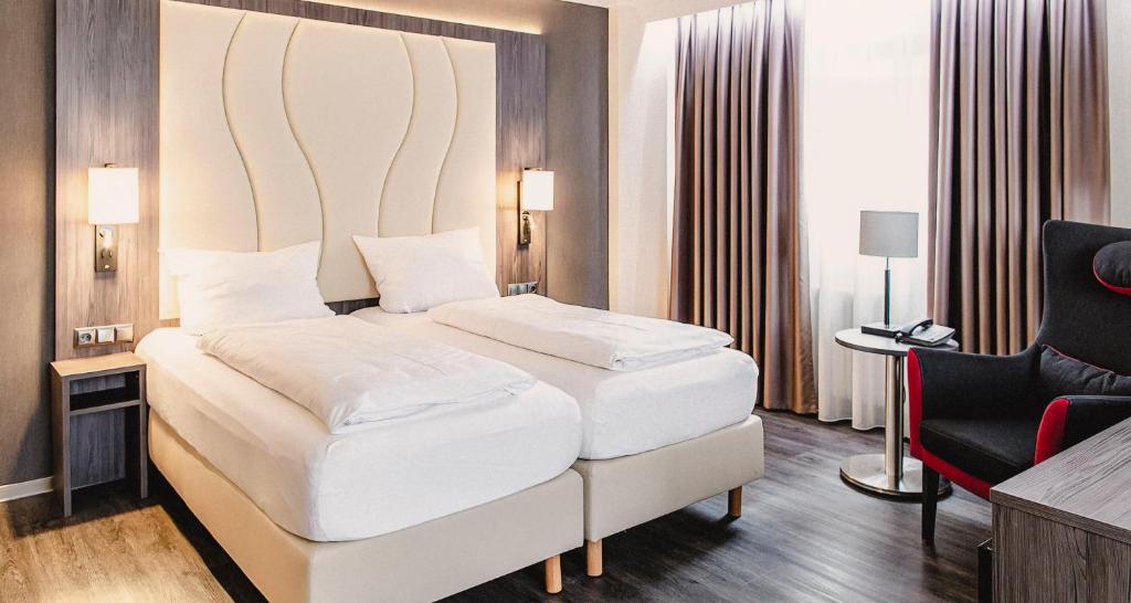 een slaapkamer met een groot wit bed en een stoel bij PLAZA Hotel Föhr am Bodensee in Friedrichshafen