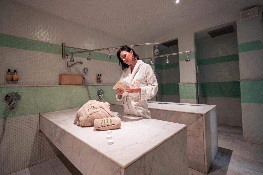 una donna in piedi in un bagno con lavandino di New Hotel Piscine Wellness & Spa a Casablanca