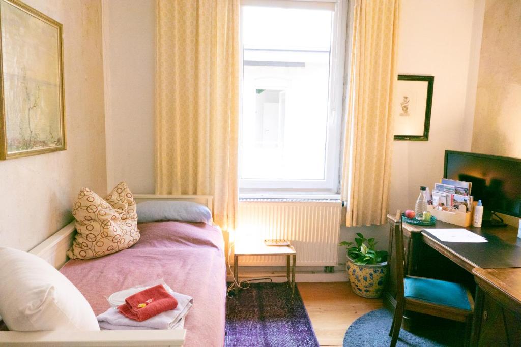 a bedroom with a bed and a desk and a window at Zimmer in Künstlerwohnung in Stuttgart
