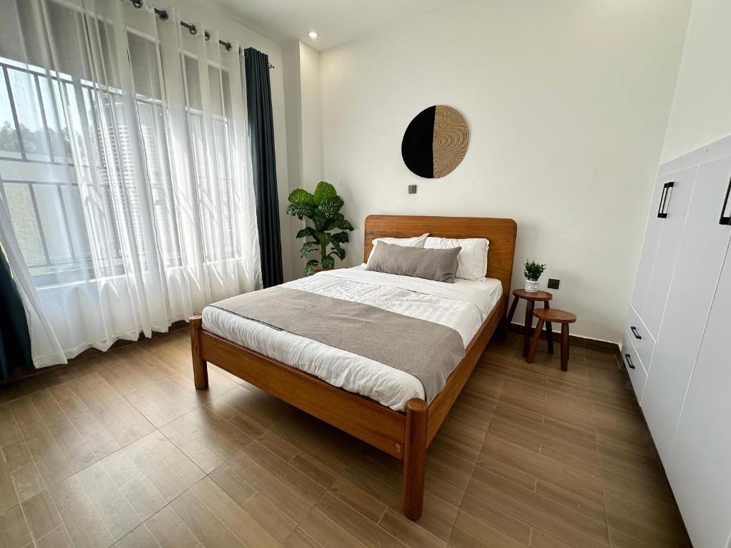 1 dormitorio con 1 cama con paredes y ventanas blancas en Coalescence Hotel Rwanda en Kigali