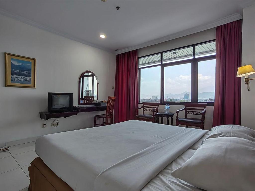 a bedroom with a large bed and a table and chairs at PIA Hotel Bandung in Bandung
