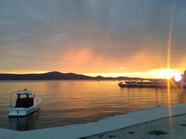 una barca in acqua con un tramonto sullo sfondo di Apartment Sveti Petar Biograd a Sveti Petar