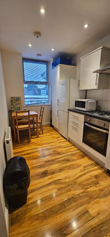 cocina con suelo de madera, mesa y sillas en Kensington Guest Rooms 98, en Londres