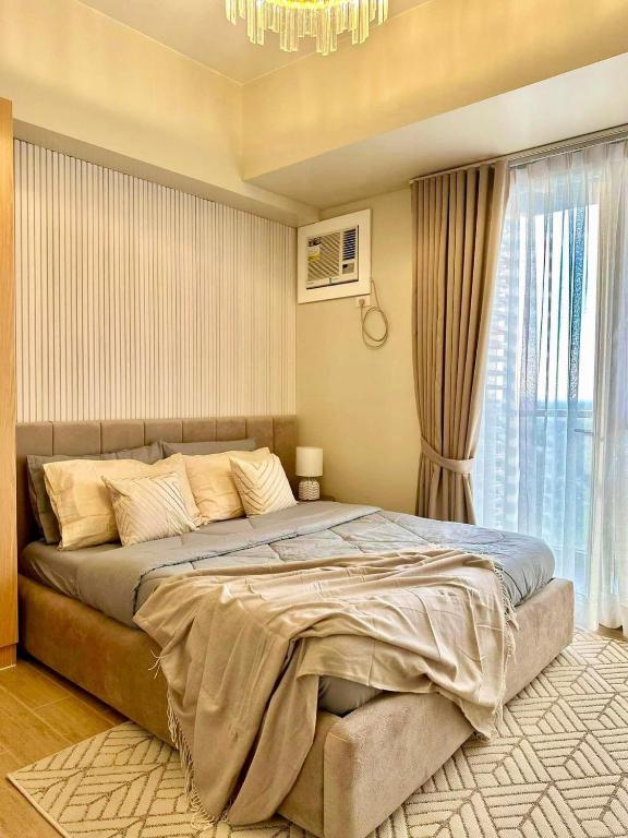 a bedroom with a large bed and a chandelier at The Palladium Iloilo near Convention Center Studio unit with private balcony City View studio only in Iloilo City