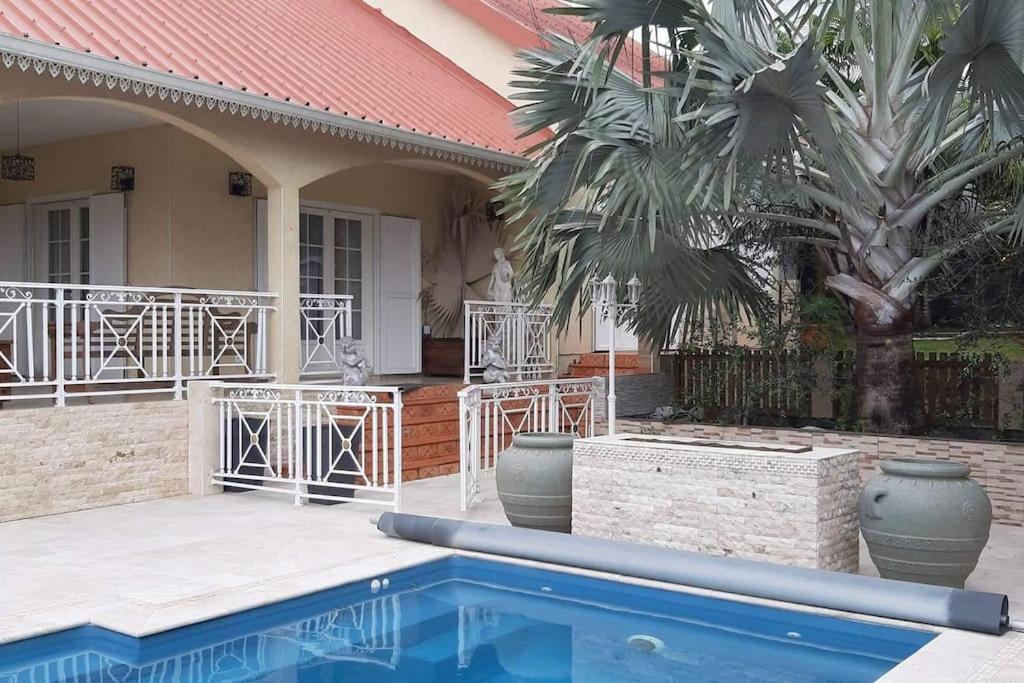 a house with a swimming pool and a palm tree at lé z'orangines in Saint-Benoît