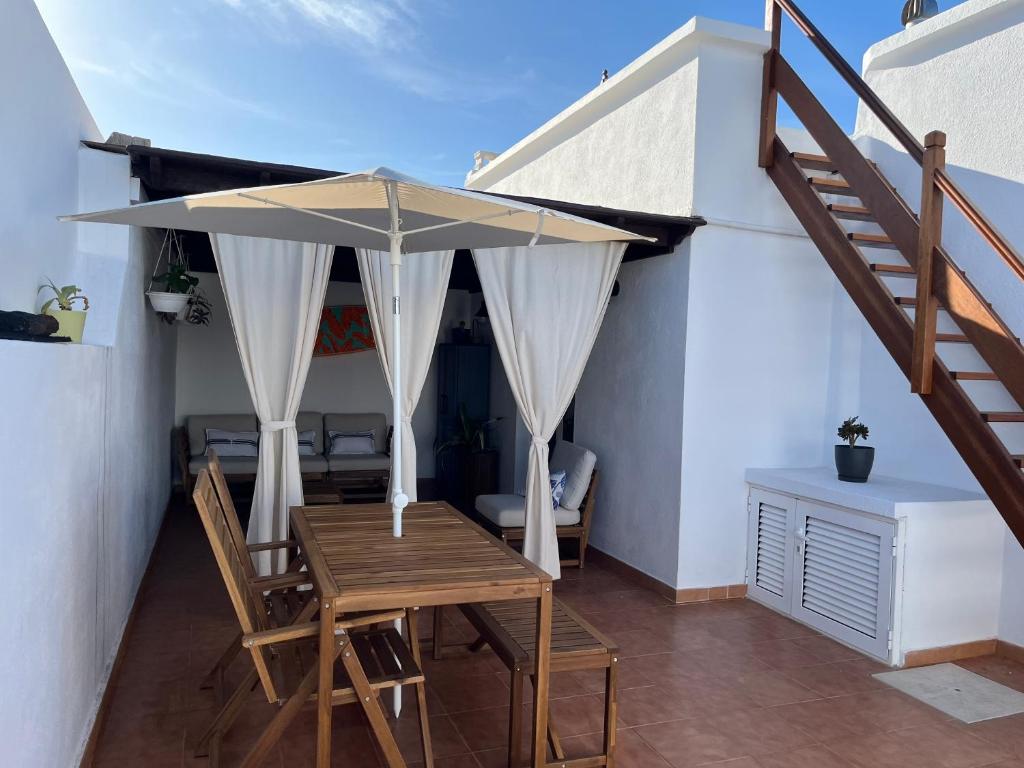 a table and chairs with an umbrella in a room at Casa Mar Azul. in Tinajo
