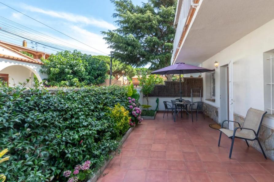 a patio with chairs and an umbrella and a hedge at Apartamento en S agaró zona tranquila in S'agaro