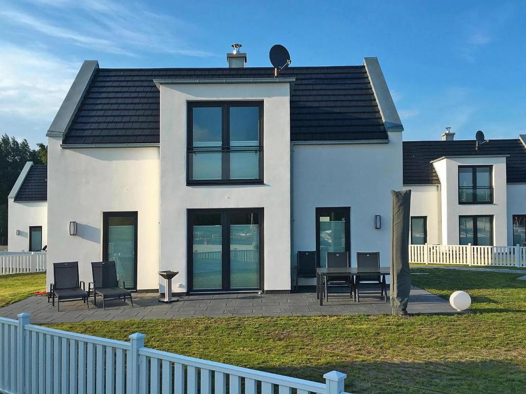 a white house with black windows and a fence at Ferienhaus am Yachthafen in Peenemünde in Peenemünde