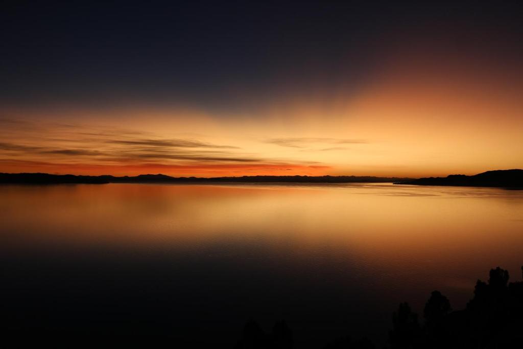 una puesta de sol sobre un gran cuerpo de agua en SUNSET Lodge Amantani, en Ocosuyo