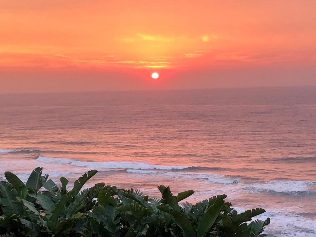 a sunset on the beach with the ocean at TRASHAVEN - Seaside Haven Backpackers in Durban